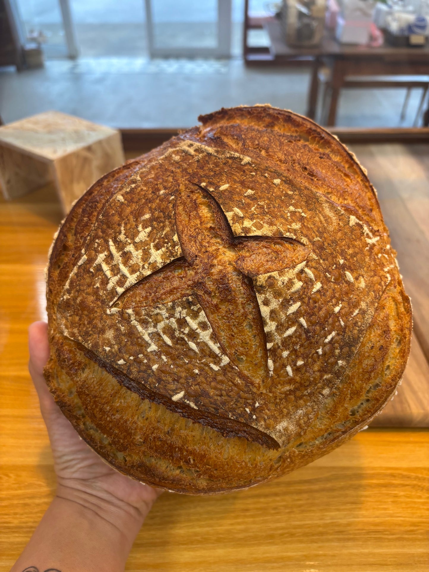 Hand holding a loaf of bread with a decorative cutout on a wooden surface
